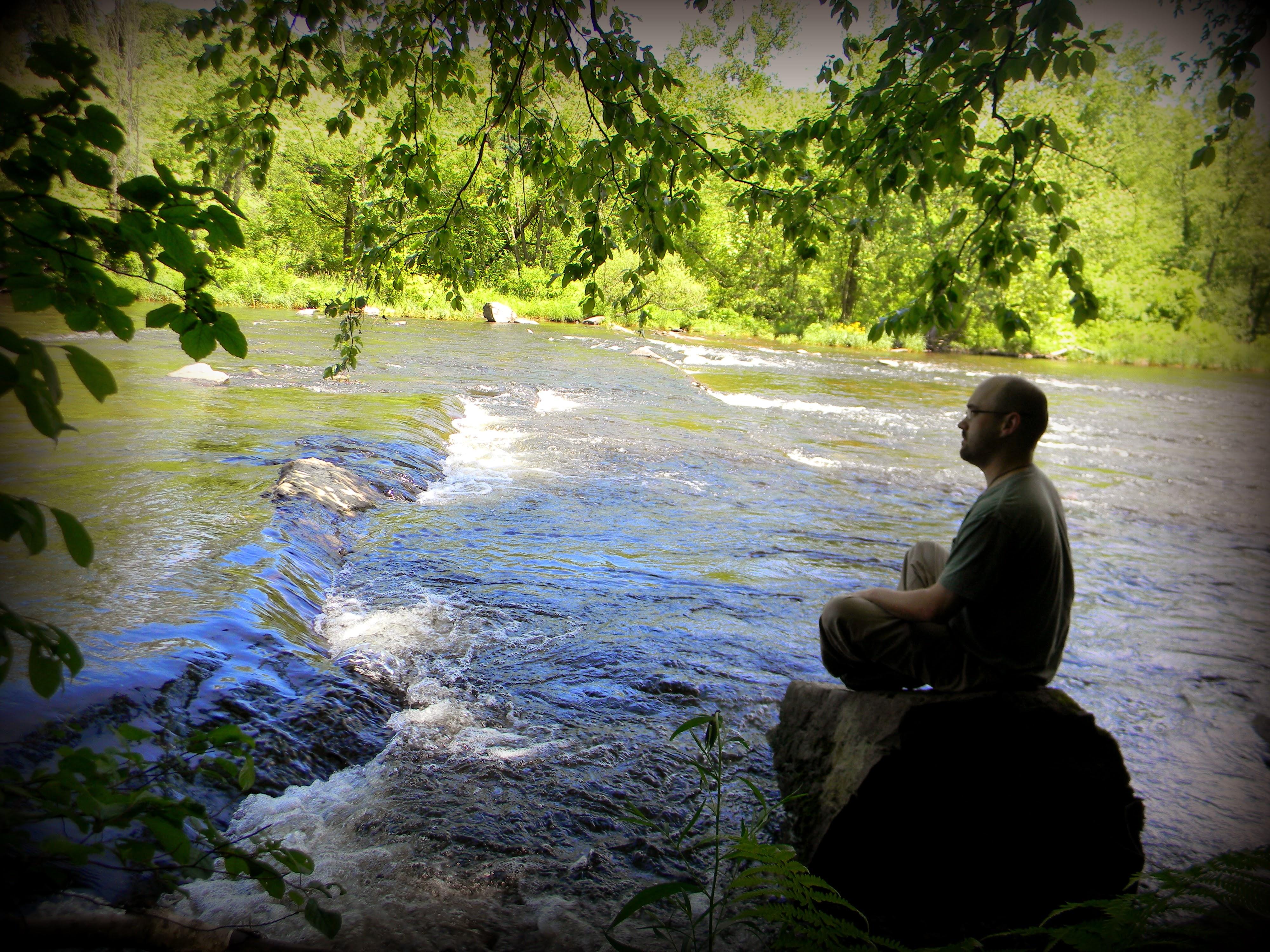 Person in contemplative meditation by flowing river - integration support